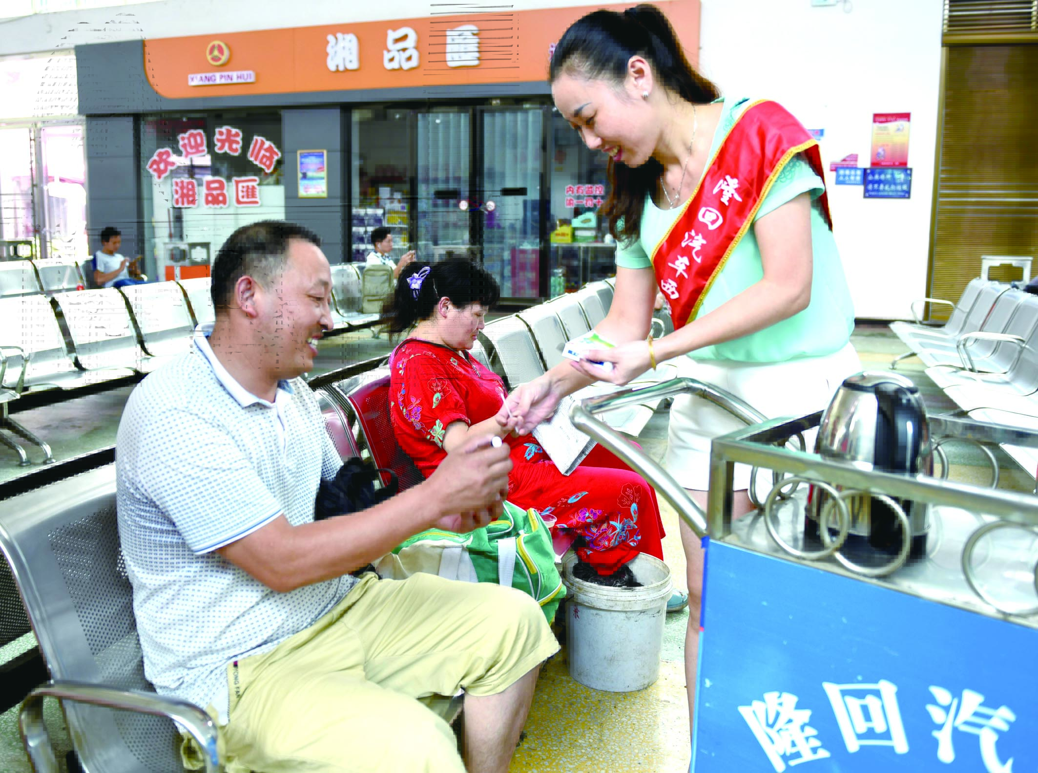 隆回分公司汽車西站工作人員正在為旅客免費贈送藿香正氣水。